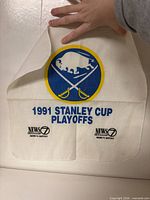 Full view of towel held upright showing Sabres logo, playoff text and sponsor logos