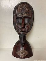 Full view of wooden mask sculpture on pedestal