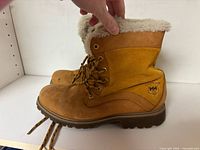 Side view of both tan nubuck boots showing faux fur collar and HH logo