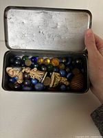 Open tin showing marbles and figurines