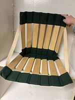 Front view unfolded showing wood slats, green canvas panels and straps