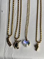 All four gold-tone necklaces with respective pendants laid out