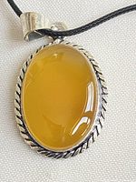 Front view of oval yellow agate pendant in sterling frame on cord