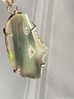 Front view of agate pendant showing banding and silver prongs