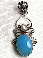 Front view of pendant showing blue chalcedony, pearl and scrollwork silver setting