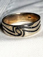 Front view of sterling silver band ring showing knot motif and 925 stamp inside