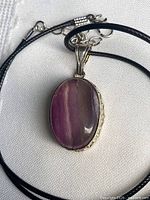 Pendant necklace laid flat showing fluorite cabochon and cord