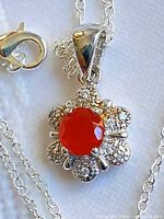 close-up of pendant showing fire opal, halo stones, bail and part of chain