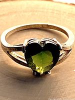 Front view of sterling silver ring with green heart-cut garnet