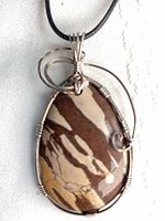 Front view of teardrop zebra jasper pendant with silver wire wrap on black cord