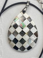 Close-up of checkerboard shell inlay pendant on cord