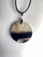 Front view of round agate druzy pendant on cord