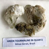 Three quartz matrix pieces with visible green tourmaline crystals and locality label