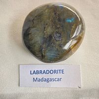 Front view of polished labradorite palm stone showing iridescence