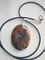 Front view of oval millefiori pendant on blue cord necklace