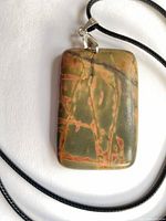 Front view of rectangular Picasso jasper pendant on black cord
