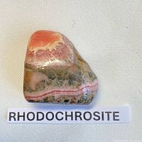 Front view of polished rhodochrosite showing pink and grey banding with label