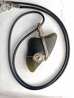 Front view of wire-wrapped green sea glass pendant on black cord