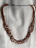 Full view of necklace laid flat showing three strands and clasp