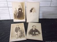 All four antique portraits displayed on dark surface