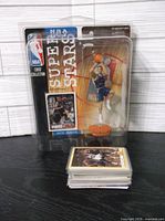Sealed NBA Super Stars action figure with stack of trading cards