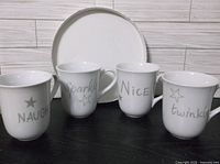 Front view of four mugs showing all silver lettering