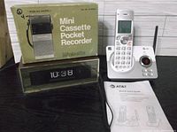 Overview of all three electronic items: Realistic recorder box, GE flip clock, AT&T cordless phone with guide