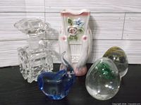 Group shot of perfume bottle, ceramic vase, blue heart figurine, two egg paperweights
