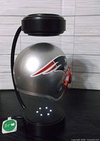Full view of levitating Patriots helmet on base with power cord visible