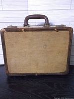 Front of tan canvas suitcase showing wear
