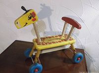 Side view of wooden giraffe ride-on showing body, wheels, handle