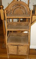 Full view of wicker shelf unit showing three shelves, arched backrest, and lower cabinet
