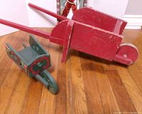 Red wheelbarrow and green wheelbarrow on hardwood floor