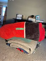 Stack of blankets, top red and black fleece, others under