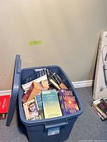 Blue plastic tote filled with assorted paperbacks, lid visible