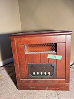 Front view of compact wood-cabinet space heater showing grille, control panel and overall finish