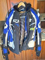 Front view of FXR snowmobile jacket on hanger showing color scheme, hood and branding