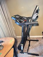 Side view of folded treadmill showing frame, branding, fold mechanism