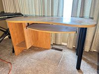 Front angle of desk showing curved top, keyboard tray, cubby and black legs
