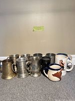 Group shot of assorted brass, pewter and ceramic mugs