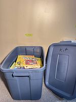 Blue Rubbermaid tote containing children’s books with lid alongside