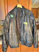 Front view of black leather bomber jacket on hanger