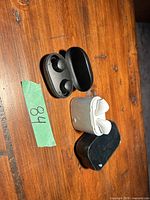 Three charging cases, two open showing earbuds: black TOZO case with earbuds, white case with white earbuds, slim black case closed