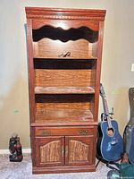 Front view of tall bookcase showing shelves, drawer and cabinet doors