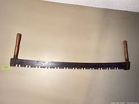 Full view of two-man crosscut saw mounted on wall