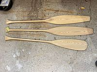 Full view of three wood canoe paddles showing handles and blades