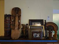 Full grouping on mantel showing carvings, mask, frames and woven fan