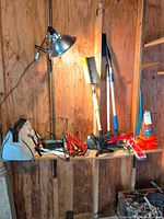 Shelf showing majority of automotive accessories including brushes, jumper cables, safety triangle, safety cones and work light