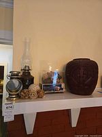 Overall lot on shelf: wood vase, oil lamp, metal lantern, packaged vase filler, loose balls