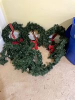 Group view of three wreaths, garland on floor